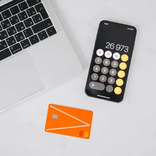 Ноутбук, смартфон с калькулятором и банковская карта на белом столе