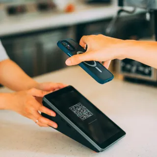 Покупатель сканирует QR-код на экране POS-терминала смартфоном, чтобы оплатить покупку