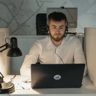 Мужчина в наушниках сосредоточенно работает за ноутбуком
