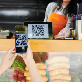 Покупатель сканирует QR-код с планшета продавца на фудтраке, чтобы оплатить заказ
