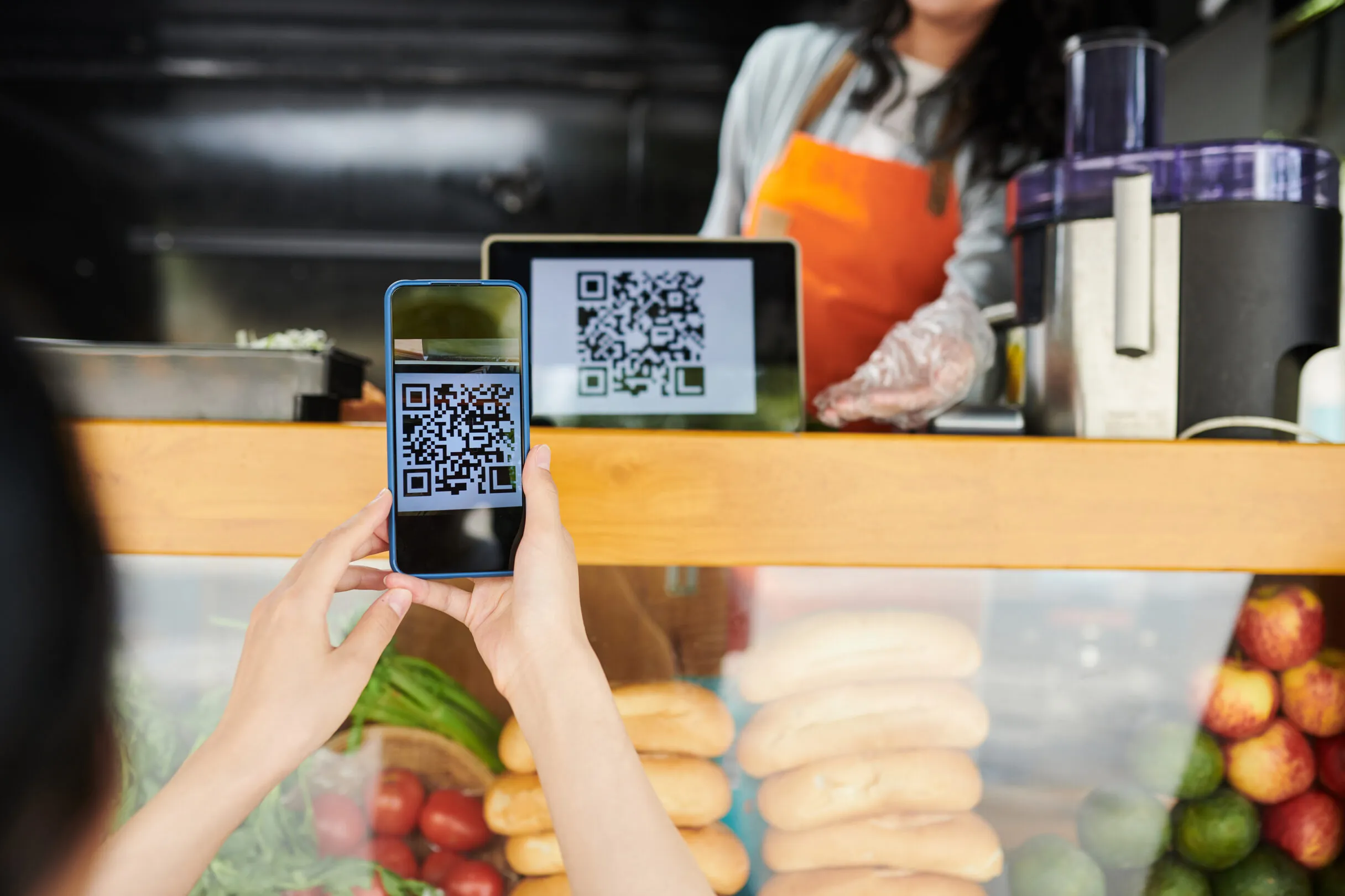 Покупатель сканирует QR-код с планшета продавца на фудтраке, чтобы оплатить заказ