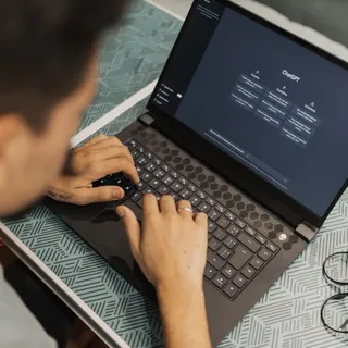 Мужчина сидит за ноутбуком и набирает запрос в чат-интерфейсе ChatGPT